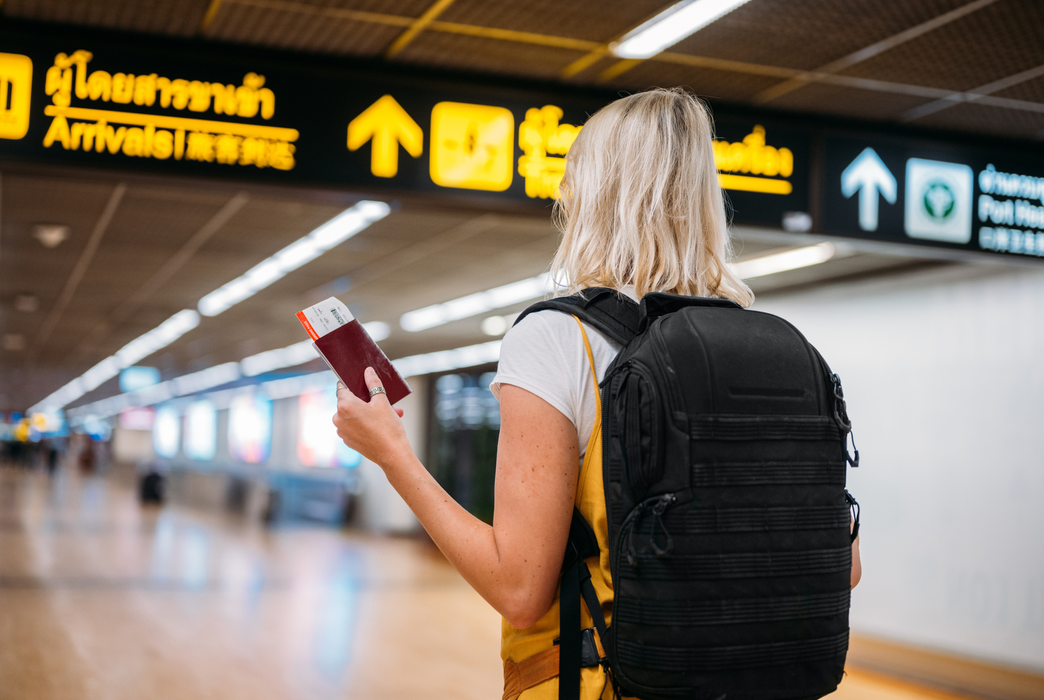 Rear view of a woman at the airport holding a passport with a boarding pass to begin her gap year in Australia 